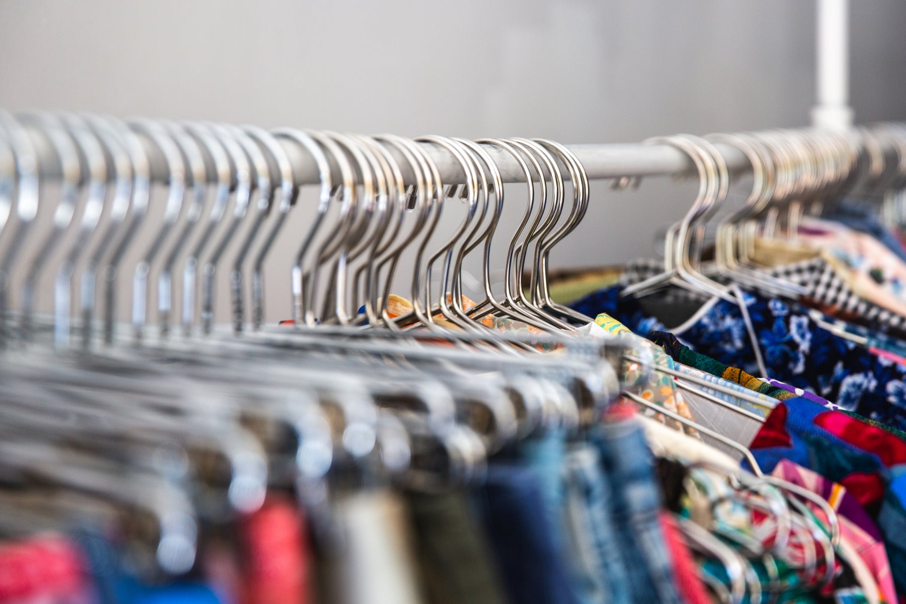 Close-up of shirts on hangers on a rack, representing our women's clothing, men's clothing, and kids' clothing collections.
